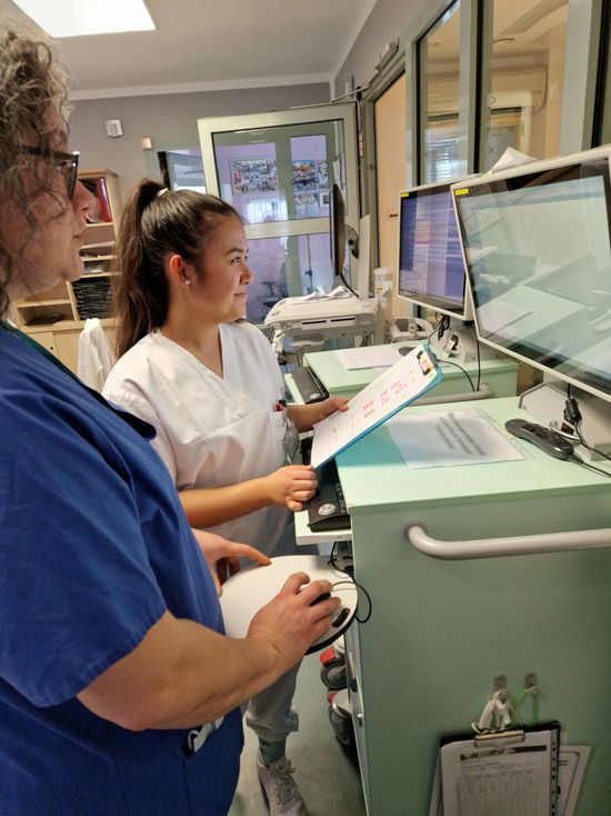 Auszubildende Leonie Hsu mit Praxisanleiterin Dana Radatus arbeiten am mobilen Visitenwagen in der digitalen Patientenakte